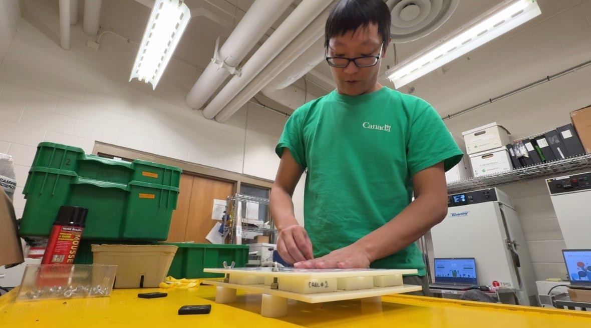 Researcher Ben Min Chang with a tray full of vine samples. He's standing in a lab.