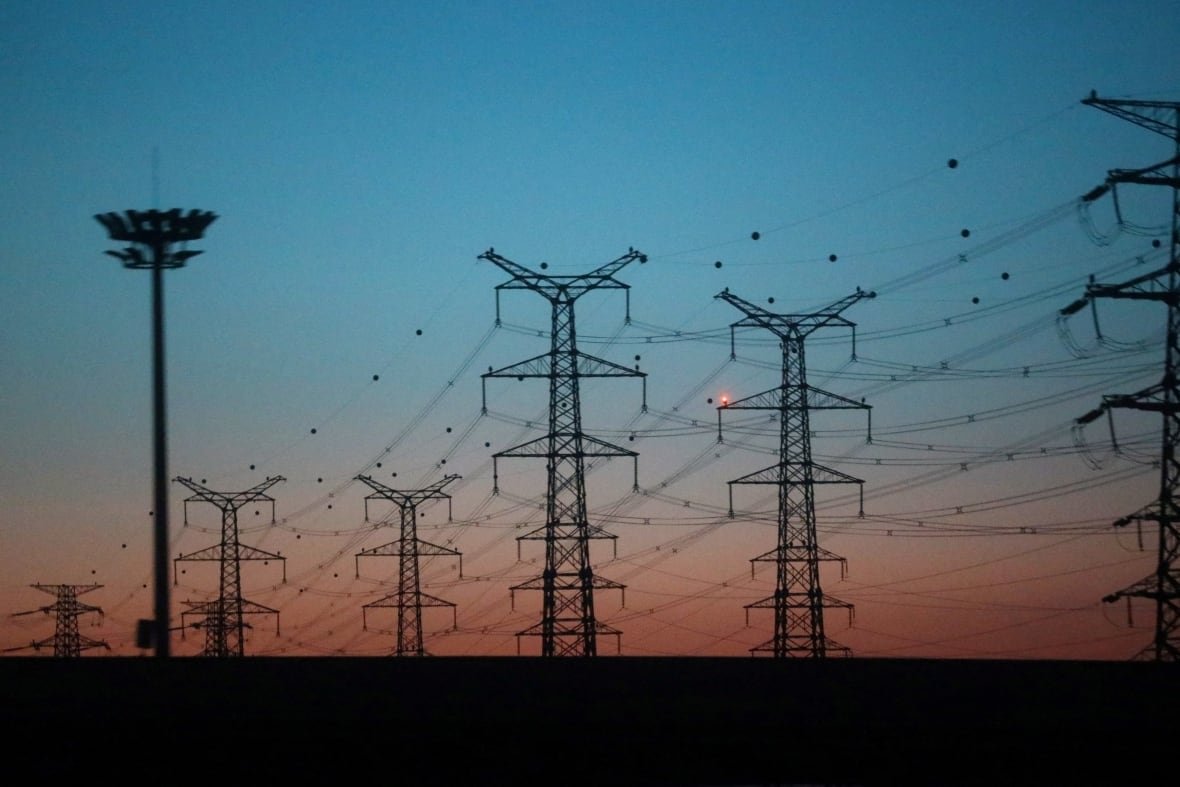 a dark pink and blue sky with outline of electrical towers