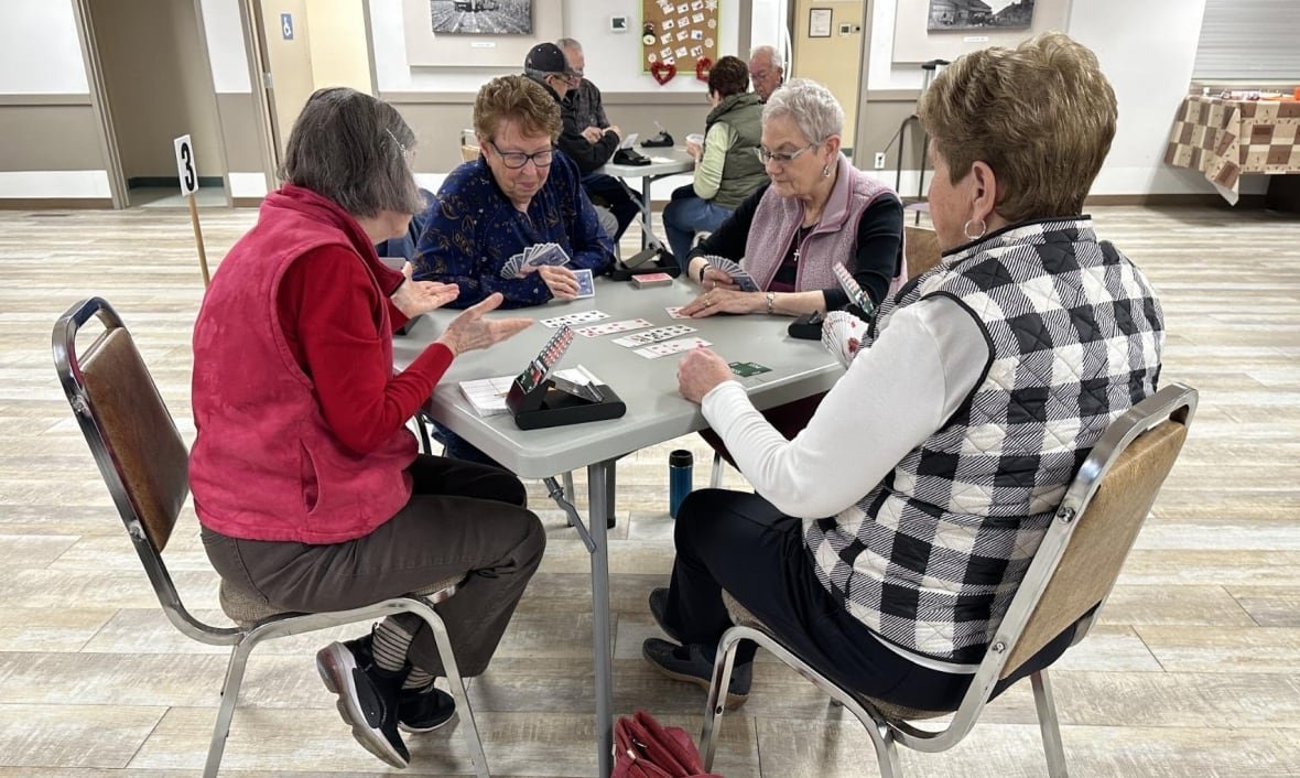 dee-glabus-bridge-friends Four women play cards at a table.