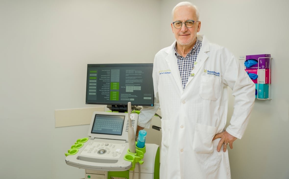 dr-laurence-klotz A man in a white doctor's coat stands next to an ultrasound machine.
