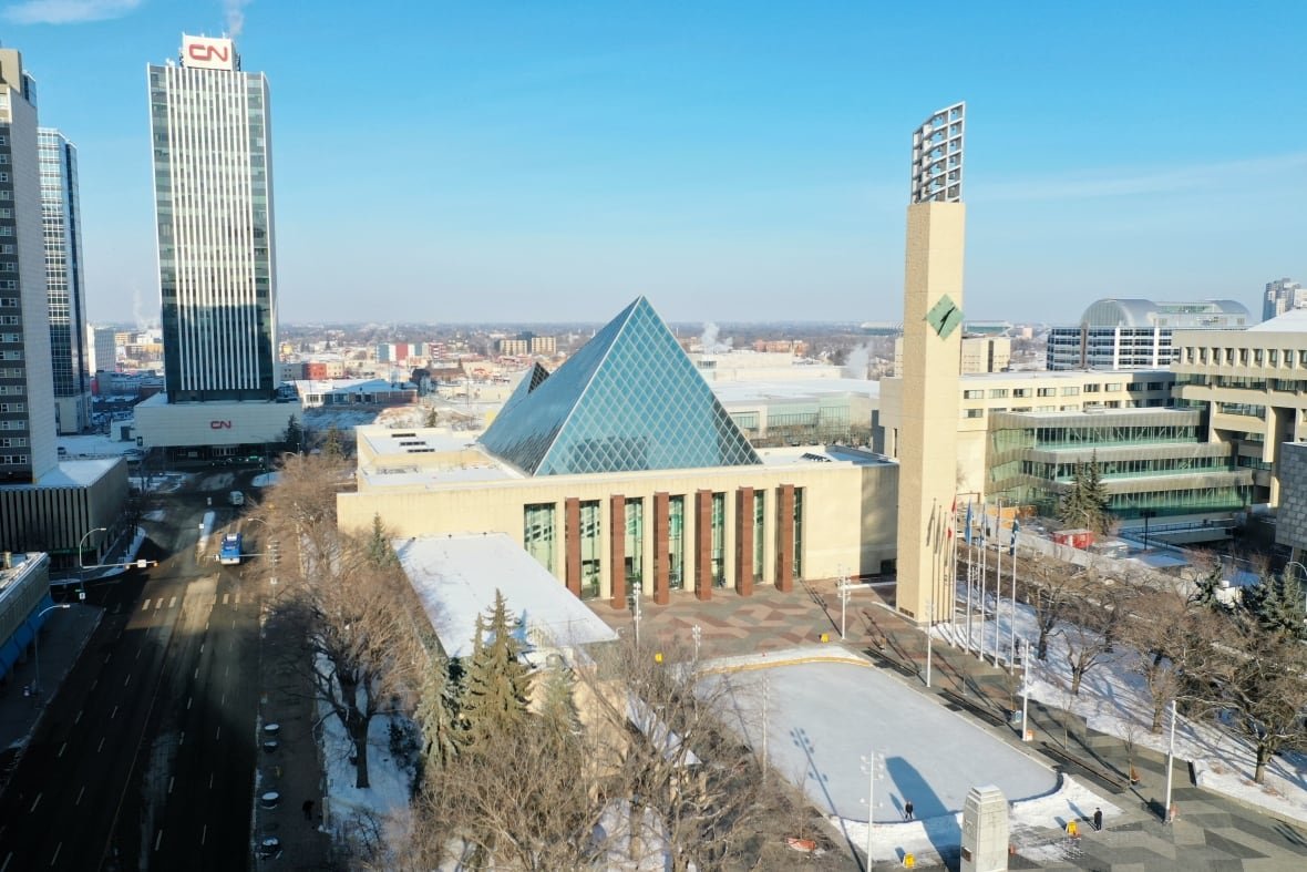edmonton-downtown-core-aerials An aerial view of Edmonton city hall in the winter: a building with a glass triangle on top, and a snowy plaza in front.