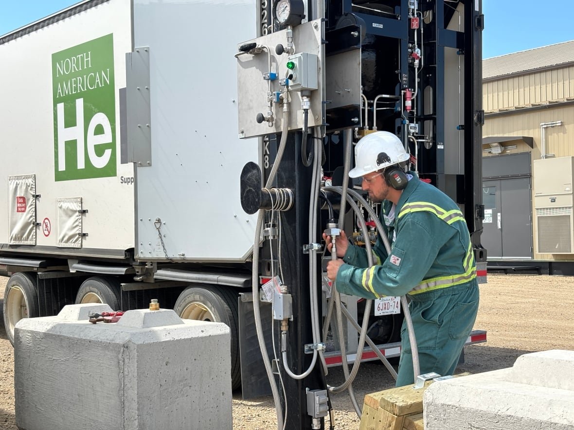 Worker in hard hat connects hoses to a large truck