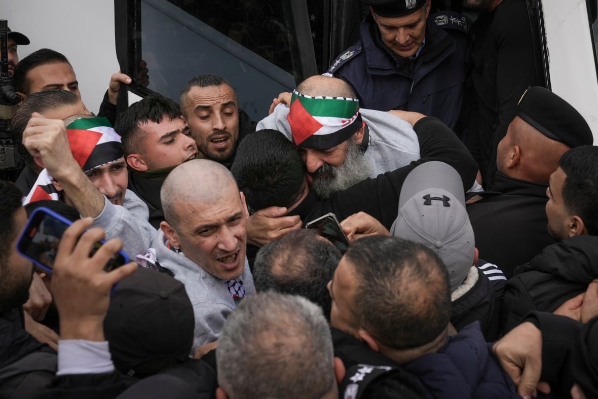 A group of men cheer and embrace or greet each other.
