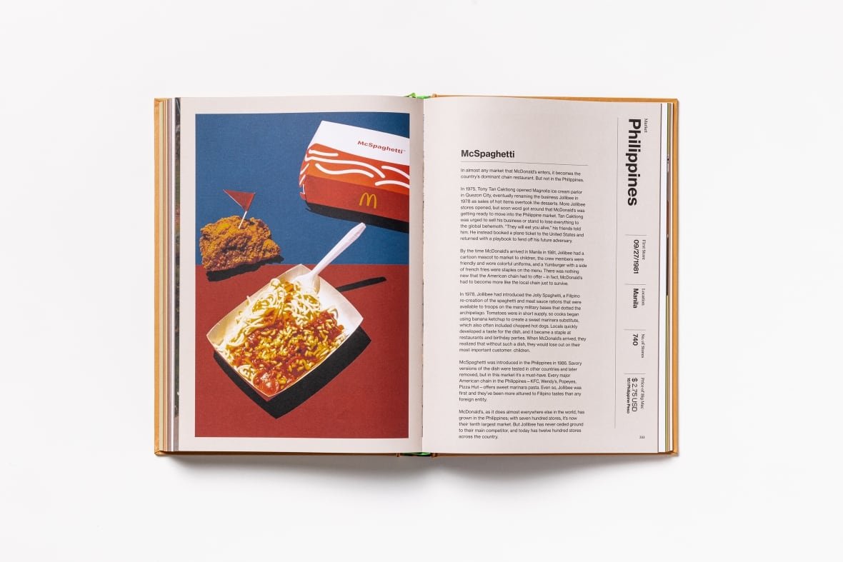 A book open and laid flat. On the left page is a large photo of a McDonald's container full of Spaghetti. On right is a page of text detailing the McSpaghetti's history.