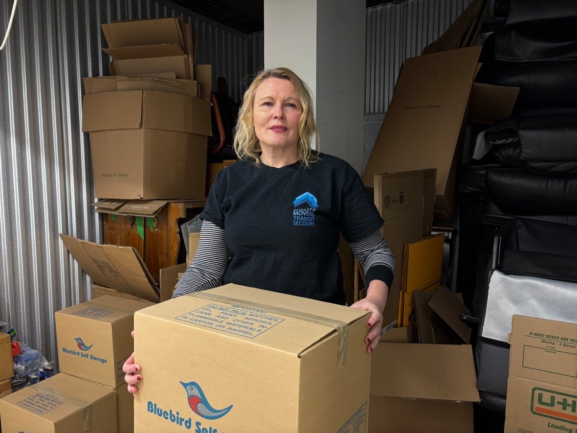 michelle-tupy A blonde woman stands in a storage unit holding a box
