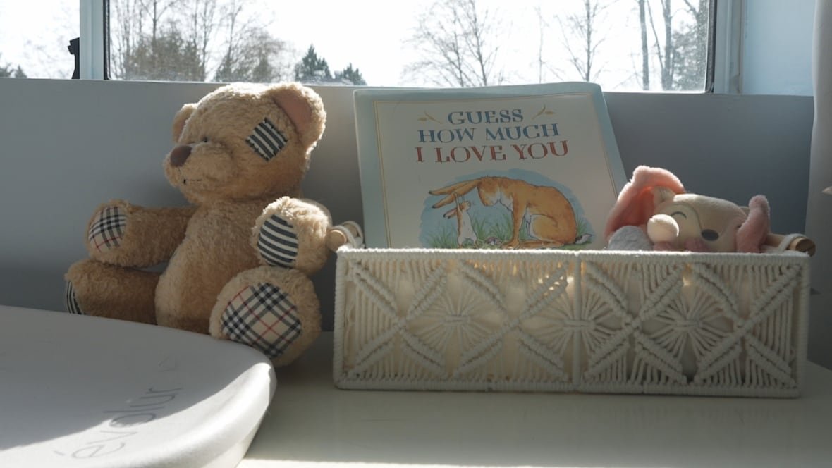 nursery A teddy bear is propped beside a diaper change pad and a book titled 'Guess How Much I Love You.'