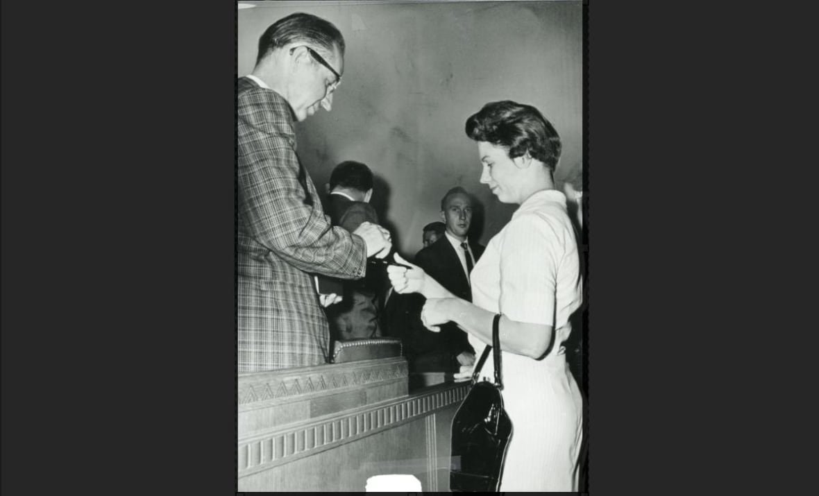 sharon-kinne-autograph A woman signs an autograph for a man in a courtroom.