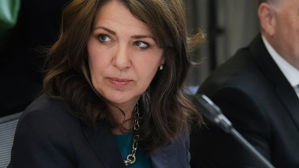 smith-1 A woman in a suit sits in front of a microphone at a table