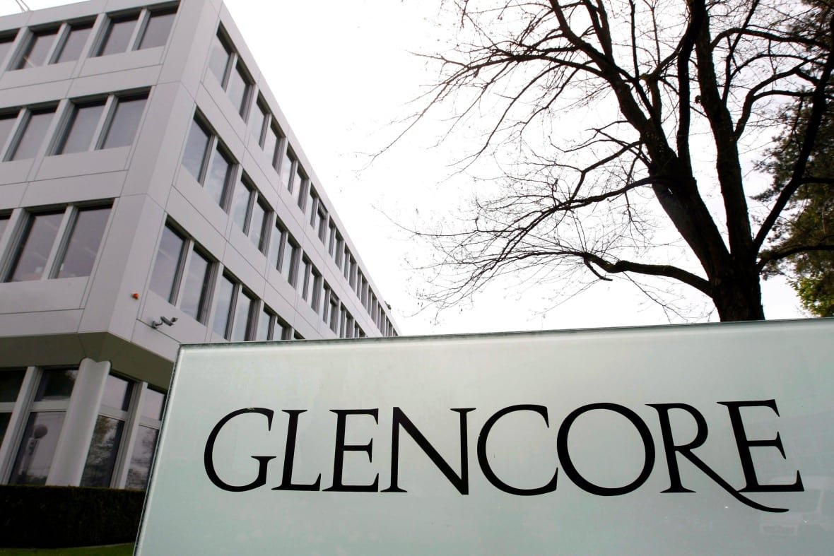 A sign written the word 'Glencore' stands next to a building.