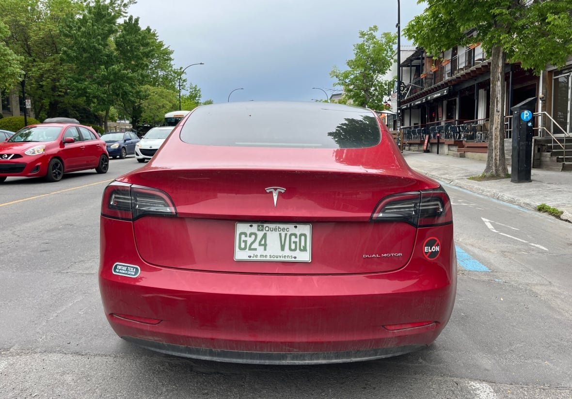 tesla-montreal-1 A red Tesla with two anti-Elon stickers.