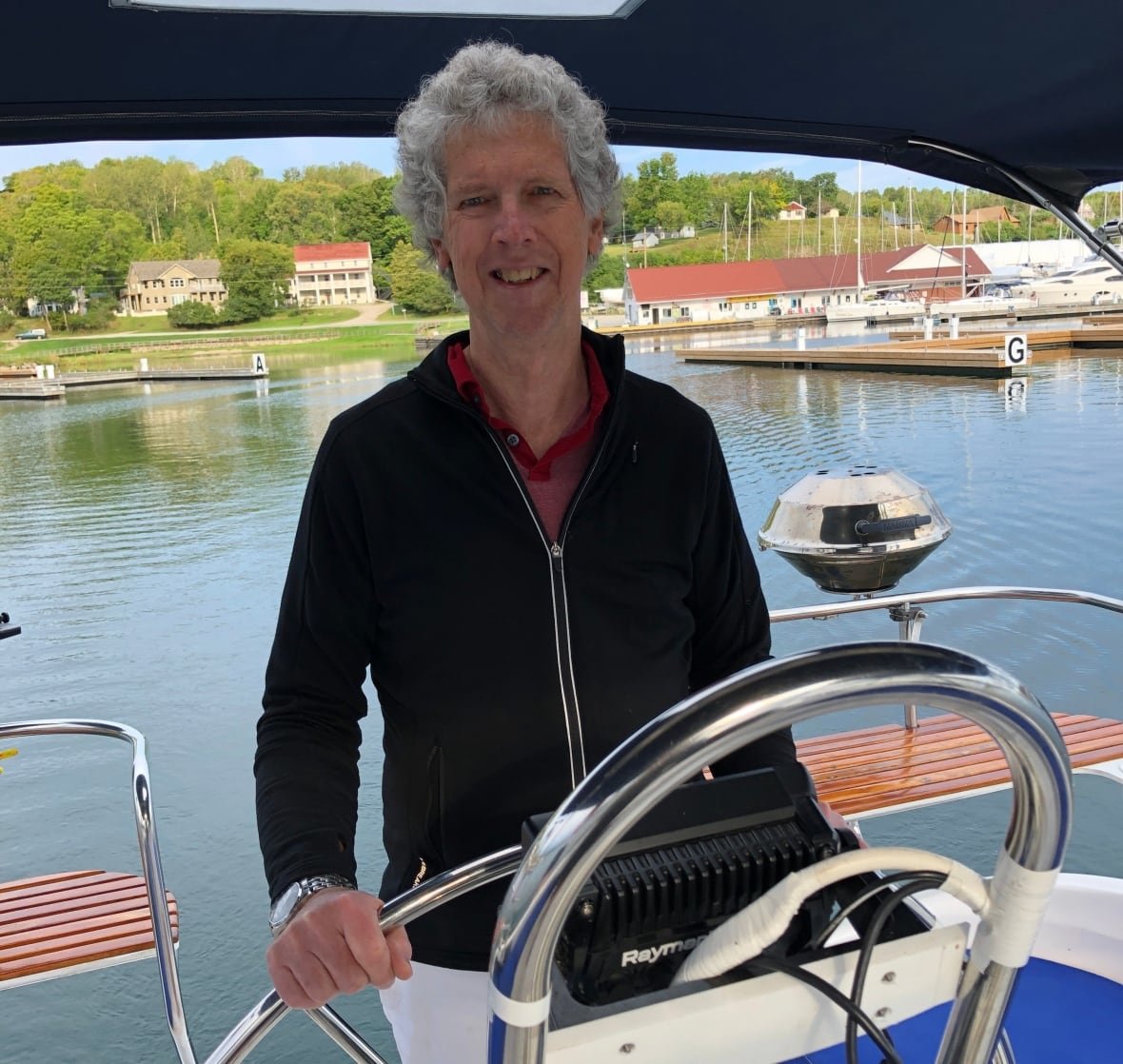 thomas-flannery A man stands at the helm of a sail boat.