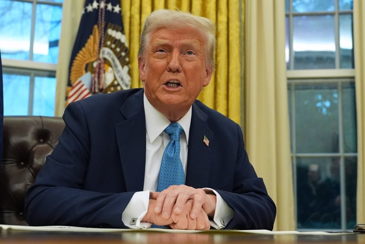 A man in a suit sits at a desk.