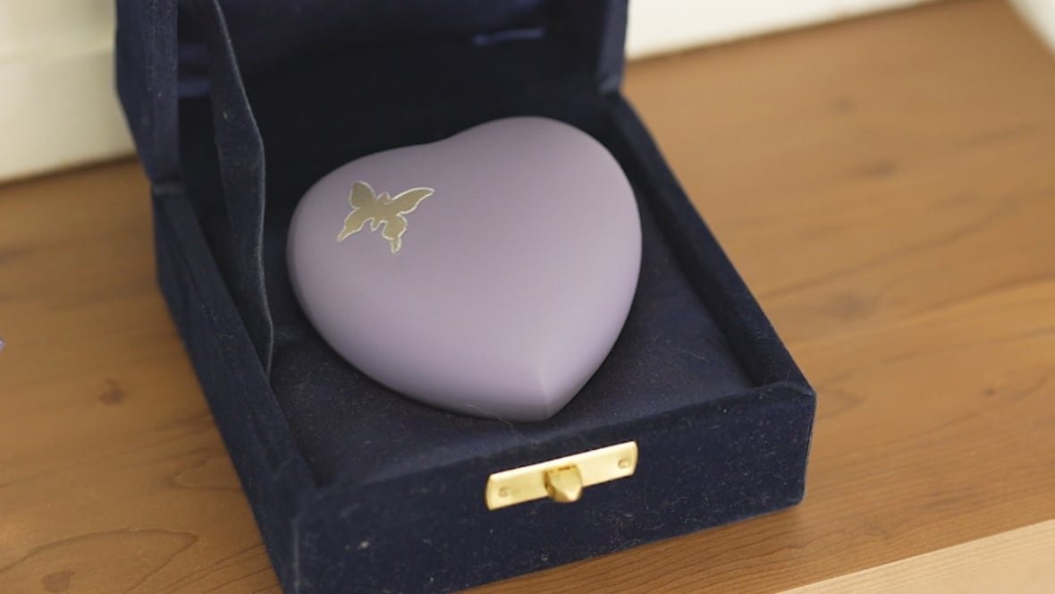 urn A heart-shaped purple urn with a gold butterfly sits on a mantle.