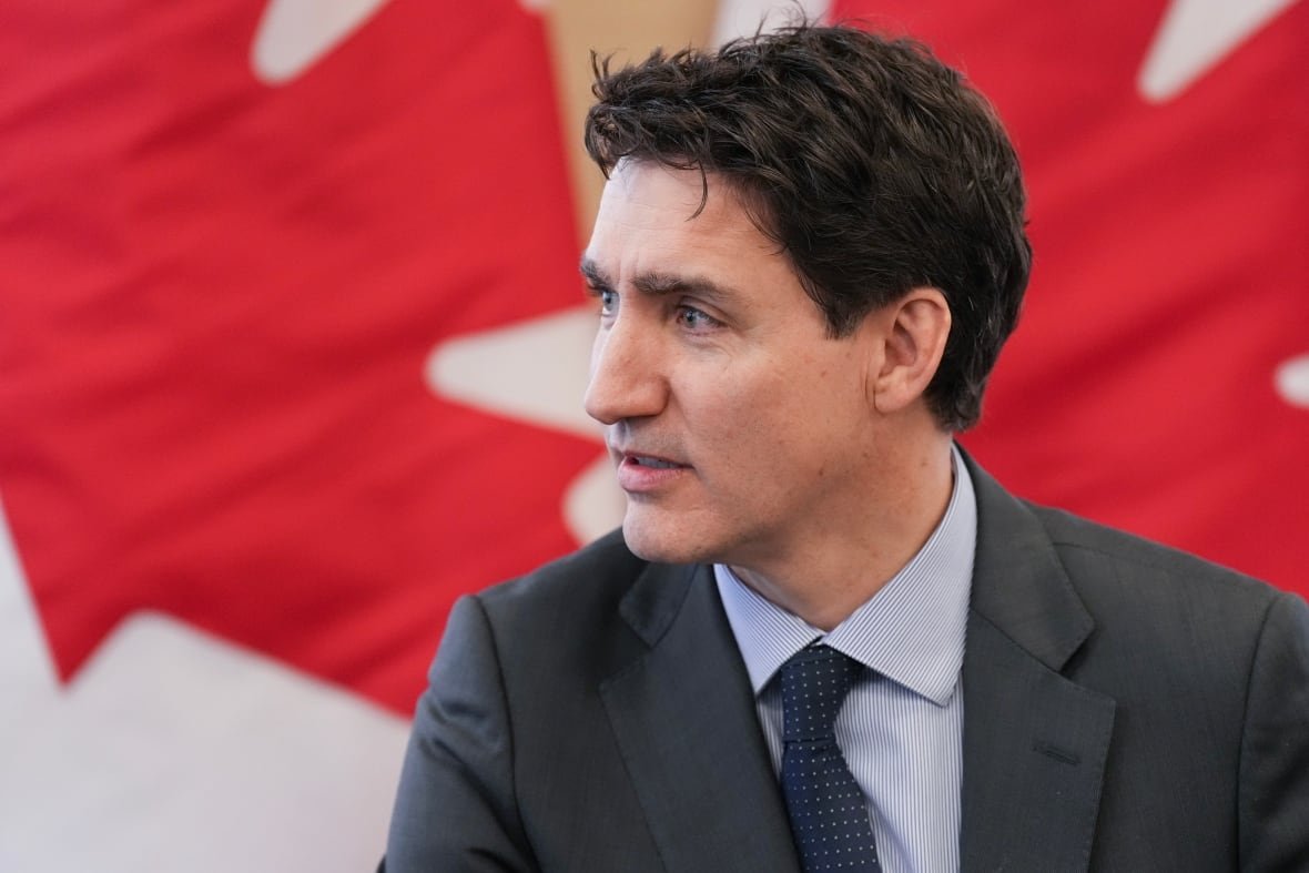 us-cda-tariffs-20250131-1 A person is seen seated in front of Canadian flags.