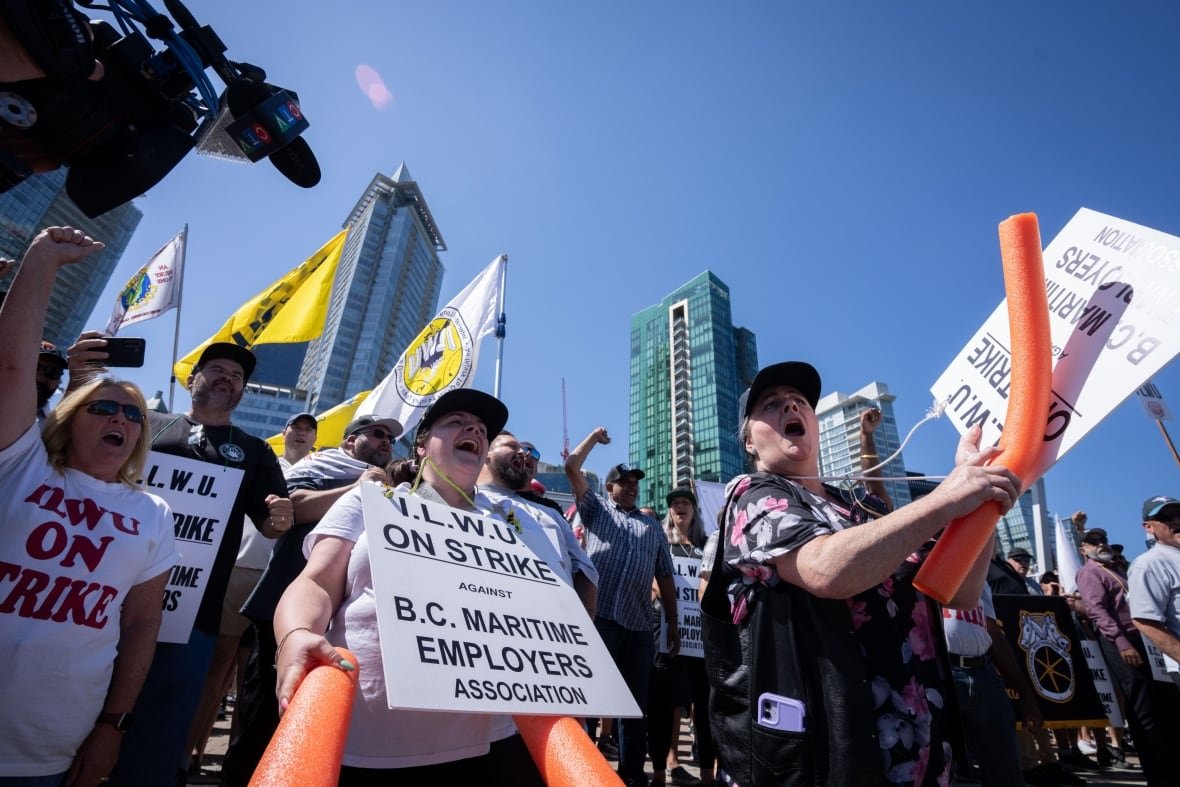 vancouver-port-strike-20230709 People wearing sandwich boards that read 'I.L.W.U. On Strike against B.C. Maritime Employers Association' are pictured at a protest.