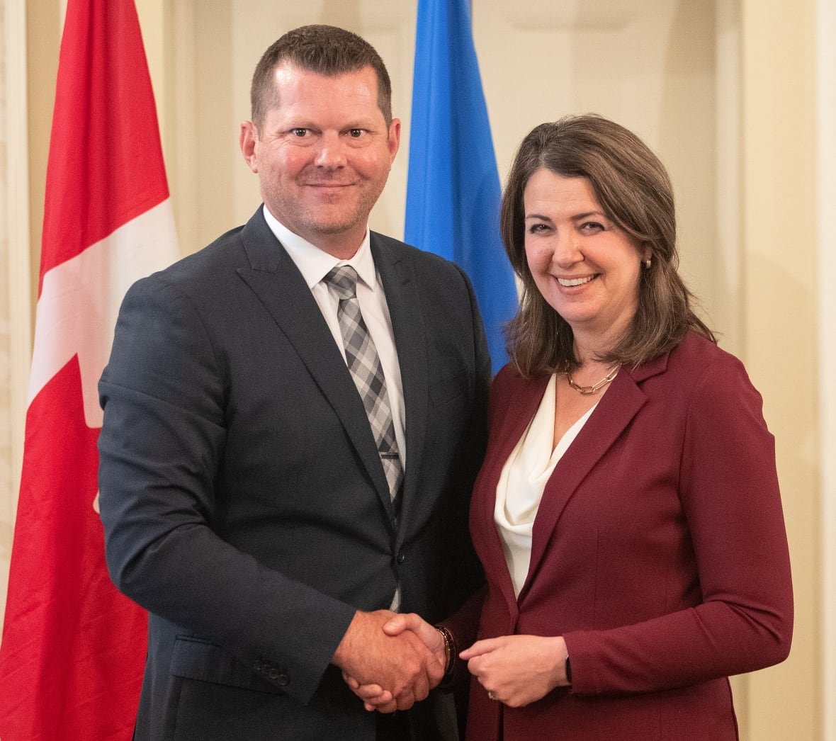 A woman and a man in suits pose for a photo.