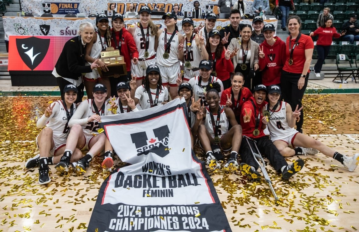 bkc-u-sports-women-20240310-1 A women's basketball team poses with a banner and a trophy on a basketball court strewn with confetti.