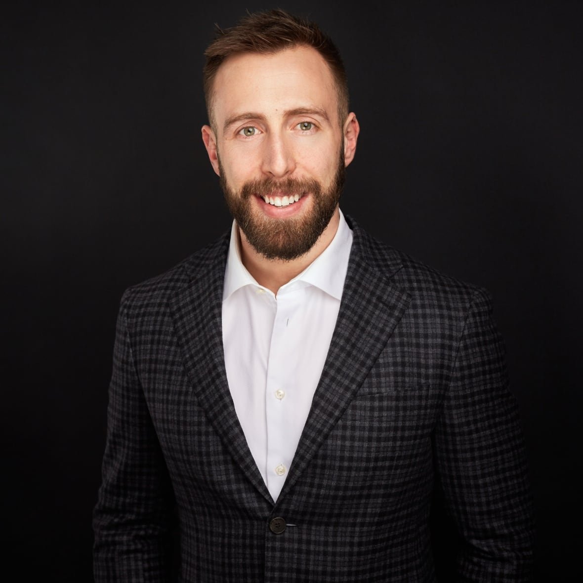 caley-shukalek a man with a beard in a suit smiles