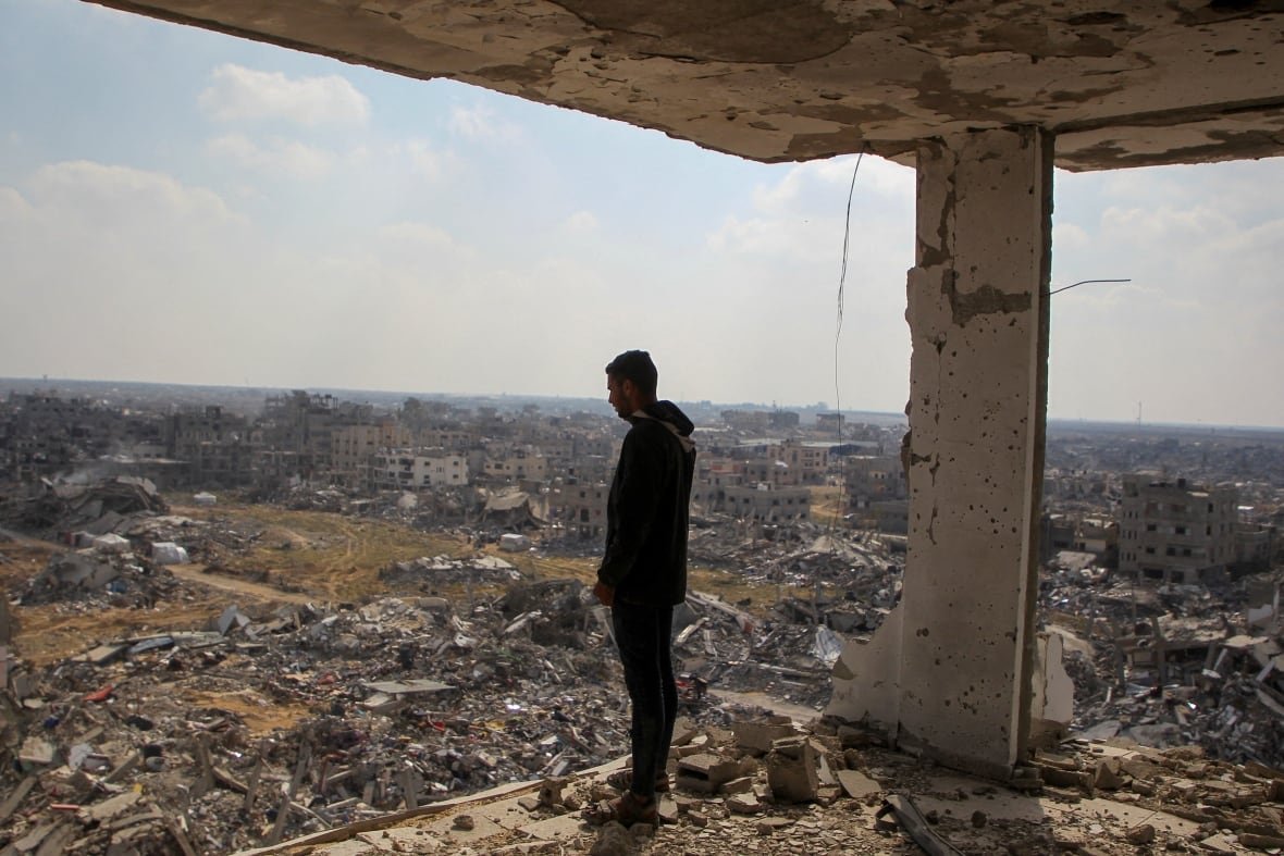 usa-israel-palestinians-gaza-trump-reaction A man stands at the edge of a destroyed building, looking down.