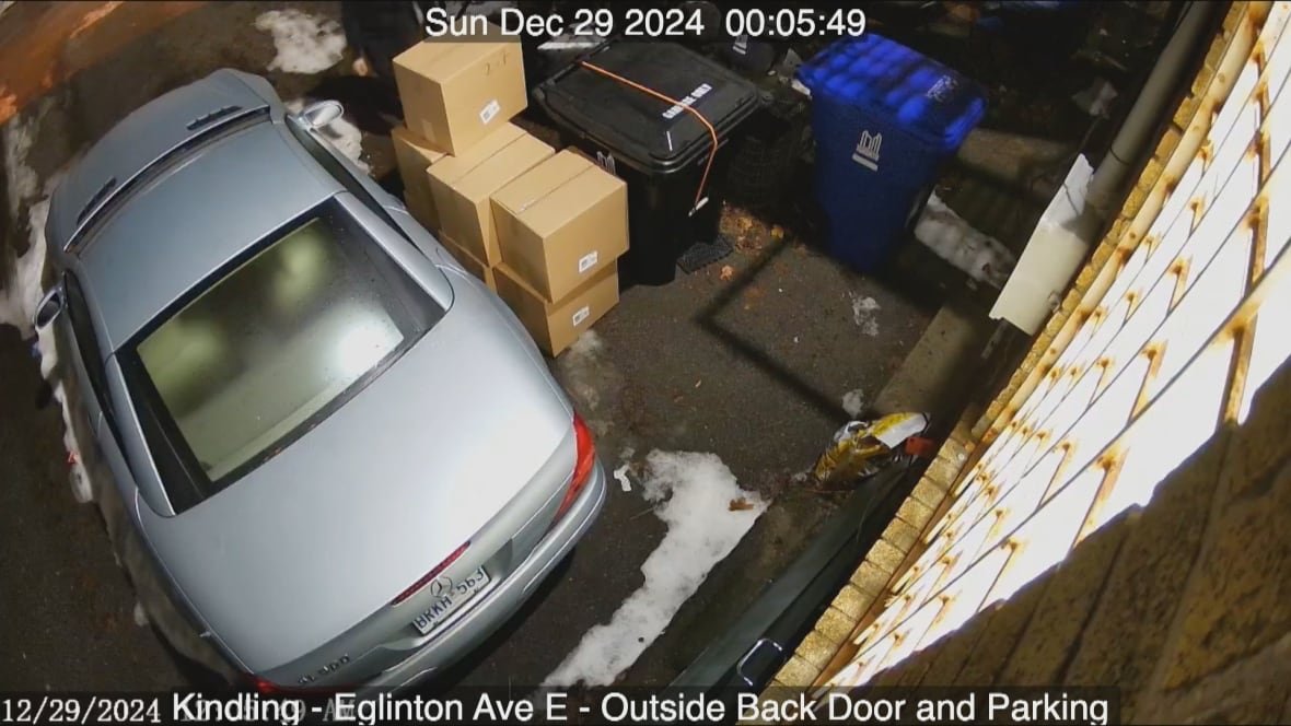 kindling-surveillance-video A screenshot from a security video that shows the back alley of the Kindling Cannabis Leaside shop. To the left is a vehicle, and to the right are a stack of cardboard boxes that have been dropped off. Just to the top of the frame, you can barely see a person by the boxes, who is later seen in surveillance footage removing them one by one.