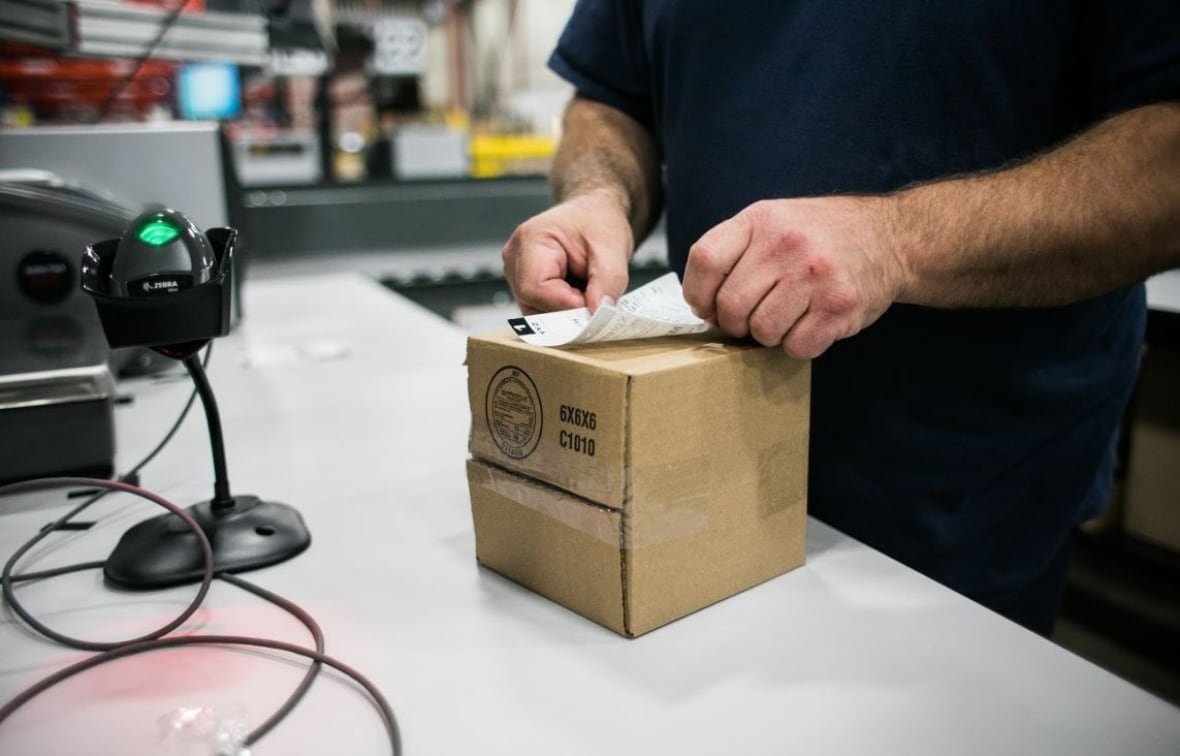 ontario-cannabis-store A close-up shot of a man sticking a label on a box of an an OCS shipment from 2018.