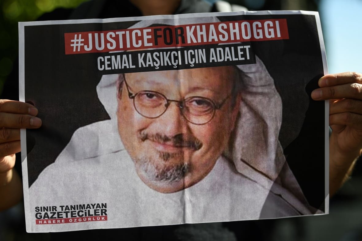 1228843501 two hands hold up a picture of a man, with the words justice for khashoggi on top.