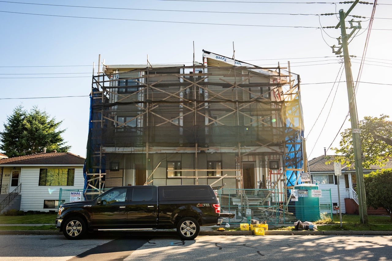 default-199 A near complete, still under construction multiplex home that is much taller than the single-family homes on either side