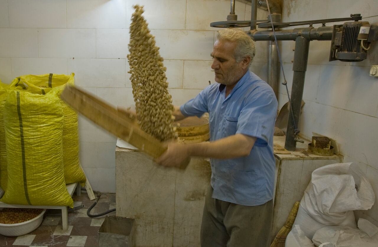 default-143 A worker throws up pistachios from a tray to clean after they are heated in preparation for final roasting.