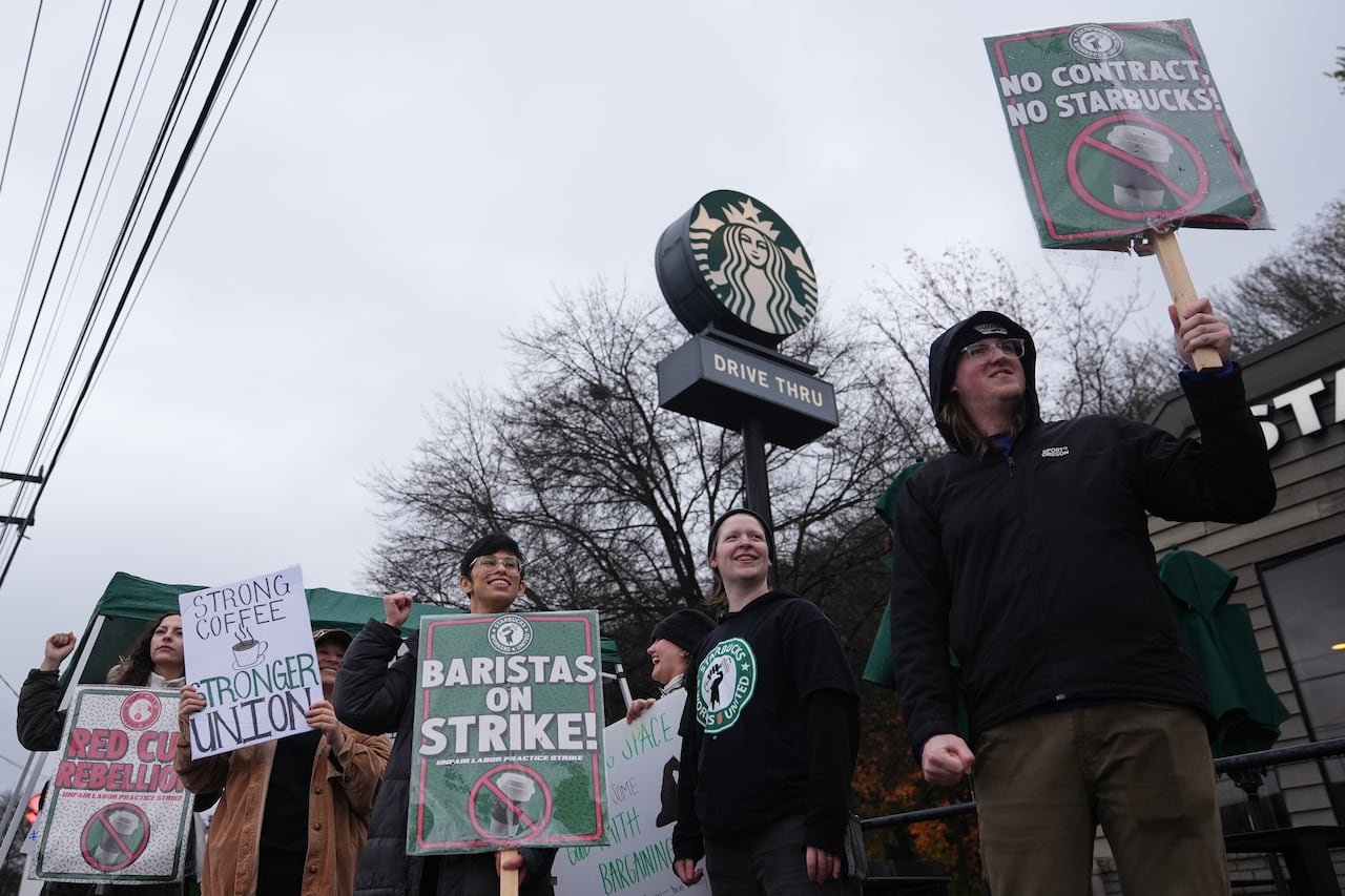 default-198 Workers hold picket signs outside of a Starbucks store.