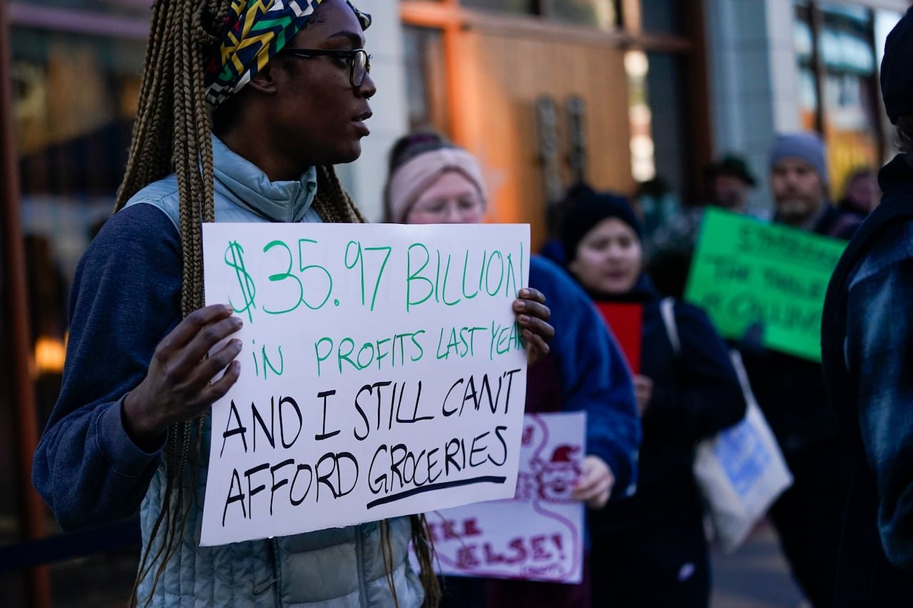 default-199 A person holds up a sign that says, "$35.97 billion in profits last year and I still can't afford groceries"